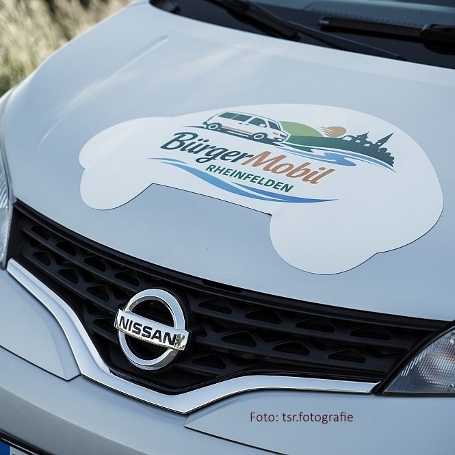Logo von BürgerMobil e.V. auf der Motorhaube eines silbergrauen Nissan-Fahrzeugs.